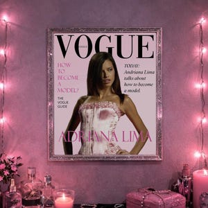 May include: A framed Vogue magazine cover featuring Adriana Lima. The cover is predominantly pink, with the Vogue logo at the top and the text "How to Become a Model?" and "Adriana Lima" prominently displayed. The image is surrounded by decorative lights.