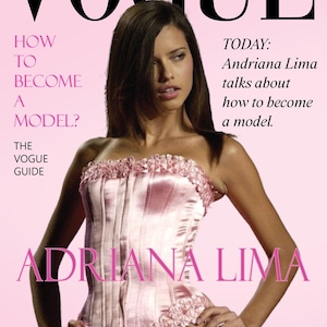 May include: Vogue Greece magazine cover featuring Adriana Lima. The cover is predominantly pink, with the Vogue logo at the top. Text includes "How to Become a Model?" and "Today: Adriana Lima talks about how to become a model."