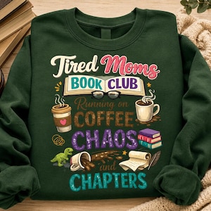 Op de afbeelding: Donkergroene sweatshirt met de tekst "Tired Moms Book Club" in wit en roze. Het ontwerp bevat koffiekopjes, boeken, brillen en de woorden "Running on Coffee Chaos and Chapters".
