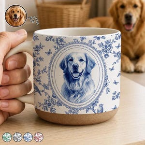 Puede incluir: Una taza de cerámica blanca con un patrón azul de flores y mariposas que presenta un retrato ovalado central de un golden retriever. La taza tiene una base natural sin esmaltar y un asa. El diseño incluye detalles botánicos y aves.
