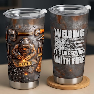 May include: Two stainless steel tumblers with clear lids. One features a welder working on a metal plate labelled DAVID, surrounded by tools. The other displays a distressed American flag graphic with the text WELDING IT'S LIKE SEWING WITH FIRE.