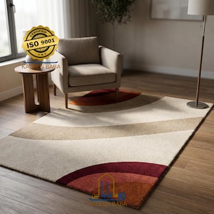 Könnte beinhalten: Ein rechteckiger Teppich mit einem geschwungenen Design in Creme-, Beige- und Burgundertönen. Der Teppich liegt auf einem Holzboden, mit einem Stuhl und einem Beistelltisch im Hintergrund. Der Teppich trägt die Aufschrift "Kalen Baba" und "ISO 9001".