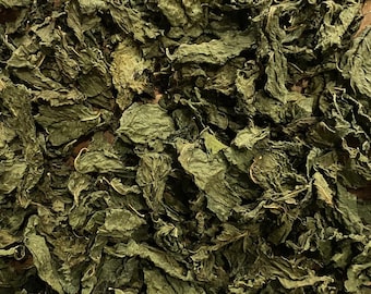 May include: Dried green leaves, possibly herbs, fill the frame. The leaves are textured and appear to be dried. A small, clear label at the bottom reads "Herbs & Simplista ALANG-ALANG" in white text with a green and yellow logo.