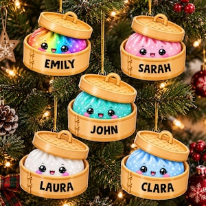 Peut inclure: Cinq décorations suspendues en forme de paniers vapeur en bambou, contenant chacune un personnage de ravioli souriant et coloré. Les raviolis sont arc-en-ciel, rose, bleu sarcelle, blanc et bleu, avec les noms EMILY, SARAH, JOHN, LAURA et CLARA.