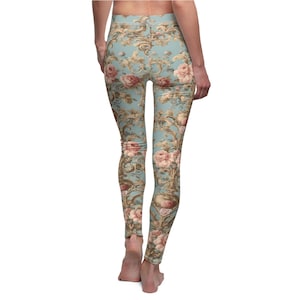 Pode incluir: Um par de leggings azuis com um padrão floral. O padrão apresenta rosas cor-de-rosa e detalhes dourados sobre um fundo azul claro.