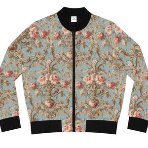 May include: A blue bomber jacket with a floral pattern featuring pink roses and gold accents. The jacket has a black zipper and black ribbed cuffs and waistband.