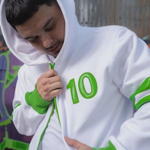 May include: A white zip-up hoodie featuring a bright green number 10 on the chest. The garment includes a green zipper, green ribbed cuffs, and green horizontal stripes on the sleeves. The hood is white and the overall design is clean and simple.