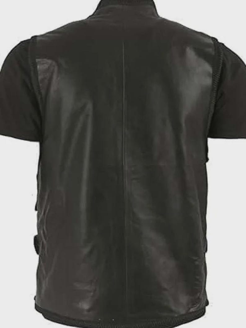 Puede incluir: Un chaleco de cuero negro con un acabado liso y s&oacute;lido, que presenta una costura vertical central en la espalda. La prenda sin mangas tiene un cuello alto y se lleva sobre una camiseta negra de manga corta, mostrando un dise&ntilde;o estructurado.