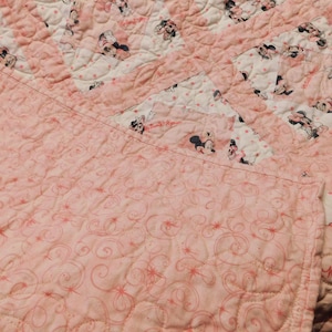 Puede incluir: Edred&oacute;n rosa y blanco con un dise&ntilde;o de Minnie Mouse. El edred&oacute;n presenta un patr&oacute;n repetitivo de Minnie Mouse sobre un fondo blanco con lunares rosas. El edred&oacute;n est&aacute; hecho de tela suave y est&aacute; acolchado a m&aacute;quina.