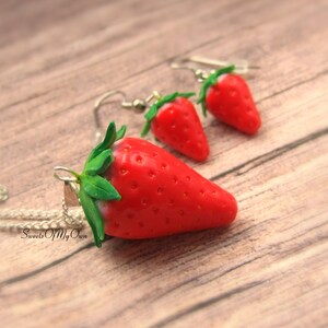 May include: A set of strawberry earrings and a necklace. The earrings and pendant are made of red and green polymer clay and have a realistic strawberry design. The necklace has a silver chain.