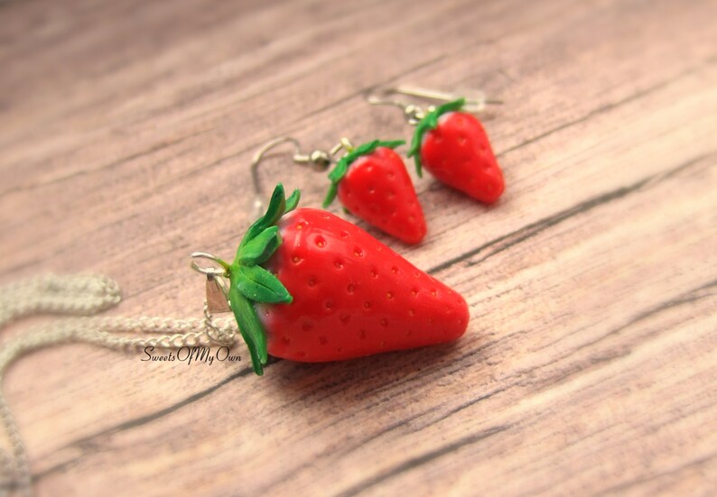 May include: A set of strawberry earrings and a necklace. The earrings and pendant are made of red and green polymer clay and have a realistic strawberry design. The necklace has a silver chain.