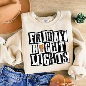 Może przedstawiać: Kremowa bluza z napisem "FRIDAY NIGHT LIGHTS" w czarno-białych literach blokowych. Litera "O" w słowie "NIGHT" przedstawia koszyk&oacute;wkę w siatce. Bluza jest połączona z niebieskimi szortami dżinsowymi i brązowym kapeluszem.