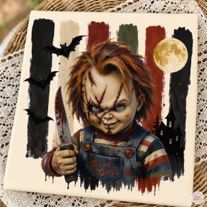 May include: A square decorative tile featuring a graphic illustration of a doll with messy orange hair, facial scars, and blue eyes. The doll wears blue overalls with the text Good Guys and holds a knife. Background includes bats and a moon.