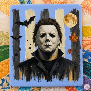 May include: A square decorative tile featuring a painted portrait of a character wearing a white mask and a dark jacket. The background includes vertical black and light blue stripes, two black bats, a full moon, and scattered orange autumn leaves.
