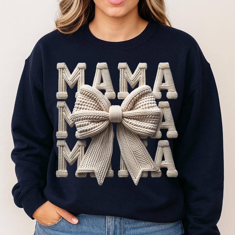 May include: Navy blue sweatshirt with the word "MAMA" in a textured, off-white font. A large, textured bow in the same off-white color is centered on the sweatshirt. The design has a 3D effect, creating a visually appealing and stylish look.