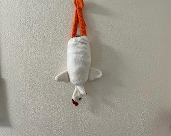 Puede incluir: Un porta pañuelos de tejido blanco con forma de pollo con patas naranjas colgando de un gancho en una pared blanca.