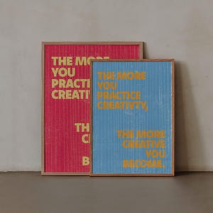 Pode incluir: Duas impress&otilde;es art&iacute;sticas emolduradas. Uma &eacute; vermelha com texto dourado que diz "THE MORE YOU PRACTICE CREATIVITY..." A outra &eacute; azul com texto dourado que diz "THE MORE YOU PRACTICE CREATIVITY, THE MORE CREATIVE YOU BECOME."