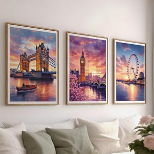 May include: Three framed art prints depicting iconic London landmarks: Tower Bridge, Big Ben, and the London Eye. Each print features a vibrant sunset sky reflected in the water, with warm gold and orange tones. The prints are displayed above a white sofa.