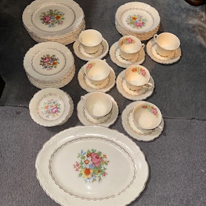 Taylor Smith Taylor TST2362 ceramic dinnerware set features a floral design on an embossed gold rim,  7 sets including fruit bowls, 44 piece