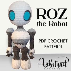 Puede incluir: Patrón de crochet para un robot llamado Roz. El robot es blanco, gris y negro con ojos azules. El patrón es una descarga PDF.