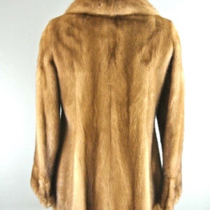 K&ouml;nnte beinhalten: Eine braune Pelzjacke mit einem gro&szlig;en Kragen. Die Jacke ist aus weichem, luxuri&ouml;sem Pelz gefertigt und hat einen klassischen, zeitlosen Stil.