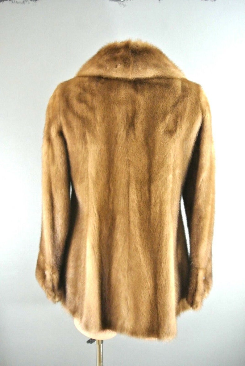 K&ouml;nnte beinhalten: Eine braune Pelzjacke mit einem gro&szlig;en Kragen. Die Jacke ist aus weichem, luxuri&ouml;sem Pelz gefertigt und hat einen klassischen, zeitlosen Stil.