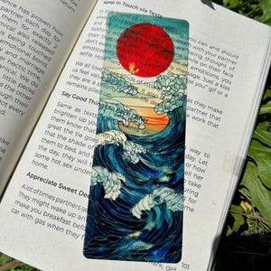 May include: A bookmark featuring a Japanese-style wave design with a red sun and a sunset. The bookmark is rectangular and has a glossy finish, with the text "Keep in Touch via Texts" at the top.