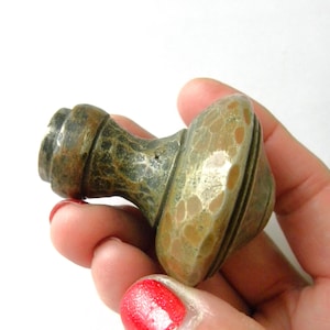 May include: A hammered brass cabinet knob with a textured surface and a rounded shape. The knob has a dark brown patina and a silver finish.