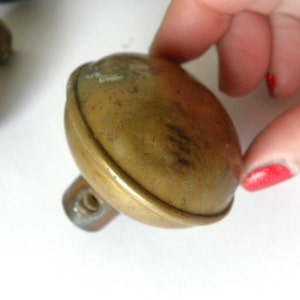 May include: A brass door knob with a round, domed shape. The knob has a threaded stem for attaching to a door.