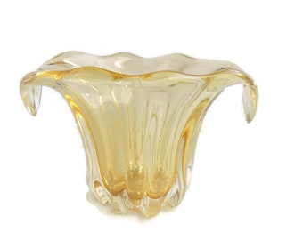 May include: A yellow glass vase with a wavy, organic shape and two handles. The vase is made of clear glass with a yellow tint.