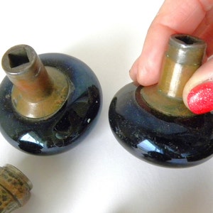 May include: Two antique door knobs with a dark blue iridescent finish and brass accents. The knobs are in the shape of a mushroom with a square hole in the top.