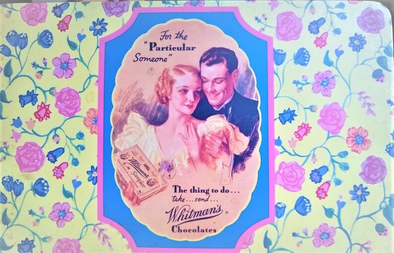 May include: A vintage Whitman's Chocolates tin with a floral pattern. The tin features a couple in a romantic setting with the text "For the "Particular" Someone" and "The thing to do... take...send... Whitman's Chocolates".