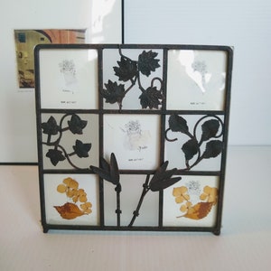 May include: A black metal picture frame with a decorative floral design. The frame has nine openings for photos, each with a different floral motif. The frame is perfect for displaying cherished memories.