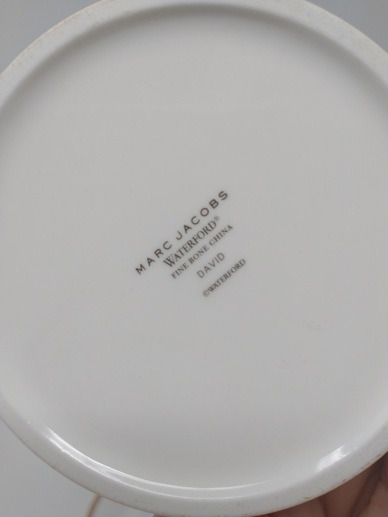 May include: White ceramic plate with the text "MARC JACOBS WATERFORD&reg; FINE BONE CHINA DAVID &copy;WATERFORD" printed on the bottom.