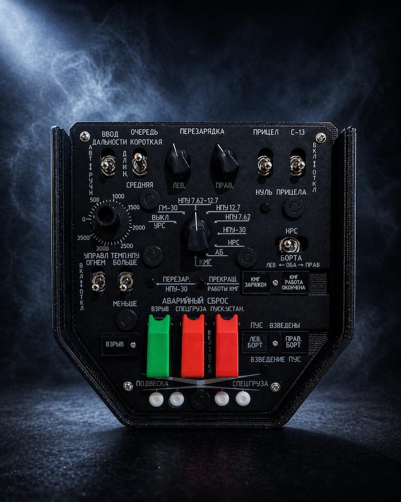 May include: A black control panel with various dials, switches, and buttons. The panel has text in Russian, including "Ввод", "ОЧЕРЕДЬ", and "ПЕРЕЗАРЯДКА". It features green and red toggle switches and a circular dial with numerical markings.