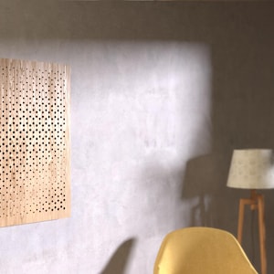 Puede incluir: Un panel acústico de madera clara con un patrón de pequeños agujeros. El panel está montado en una pared.