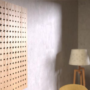 Puede incluir: Un panel de madera marrón claro con un patrón geométrico de pequeños agujeros espaciados uniformemente. El panel está montado en una pared beige claro.