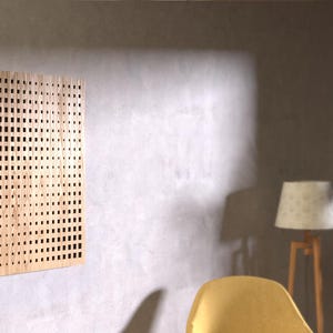 Puede incluir: Un panel acústico de madera clara con un patrón de rejilla. El panel está montado en una pared gris clara.