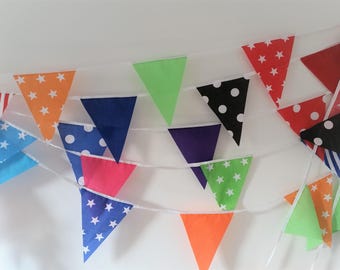 May include: A colorful bunting banner with triangular flags in various colors and patterns, including stars, polka dots, and stripes. The flags are strung together on a white string, perfect for party decorations.