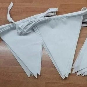 May include: A string of light blue triangular fabric pennants attached to a white fabric ribbon. The pennants are arranged in a series of pointed shapes, creating a decorative bunting banner with a clean, solid color finish throughout.