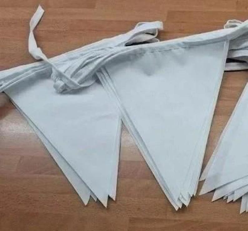 May include: A string of light blue triangular fabric pennants attached to a white fabric ribbon. The pennants are arranged in a series of pointed shapes, creating a decorative bunting banner with a clean, solid color finish throughout.