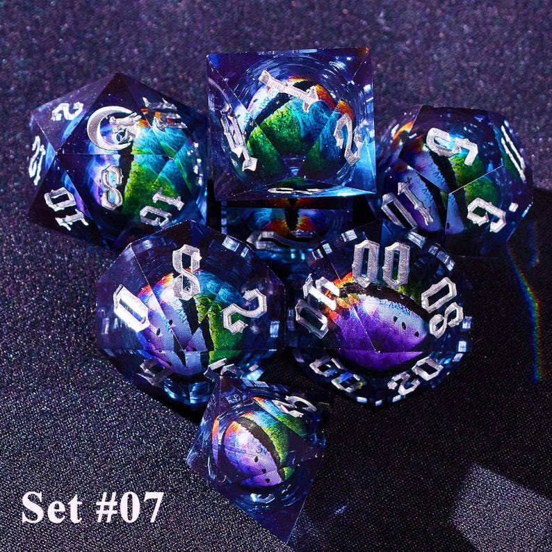 May include: A set of seven polyhedral dice with a galaxy-themed design. The dice are transparent with a blue hue, and feature silver numbering. The interior of each die has a colorful, swirling design. The text "Set #07" is at the bottom.