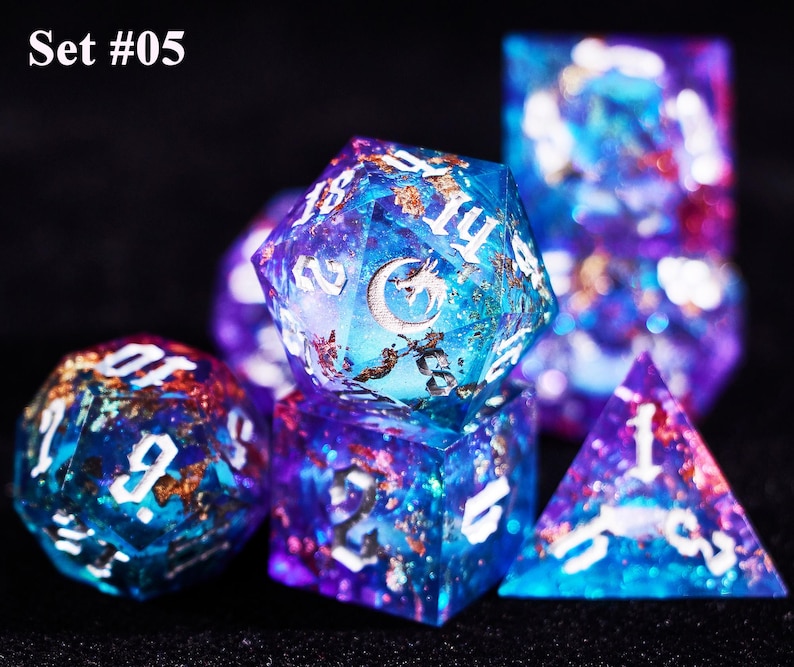 May include: Set of seven polyhedral dice with a celestial theme. The dice are a mix of blue, purple, and gold, with white numbering. The image includes a D20, D12, D10, D8, D6, D4, and a D10 percentile die. The text "Set #05" is in the upper left corner.