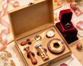 May include: A wax seal kit in a tan box containing a wooden-handled brass stamp, a gold-toned melting spoon, a glass vial of gold wax beads, and a round wooden wax warmer with a tea light candle, plus a red velvet ring box with a silver ring.