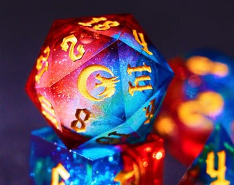 Könnte beinhalten: Ein Satz irisierender Würfel mit einem galaktischen Muster und goldenen Zahlen. Die Würfel sind mehrfarbig mit Blautönen, Rot- und Violetttönen.