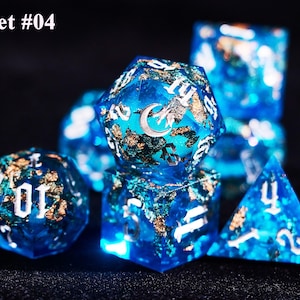 May include: A set of seven blue resin dice with gold flakes and white numbering. The dice feature a celestial design with a crescent moon and stars. The text "Set #04" is in the upper left corner.