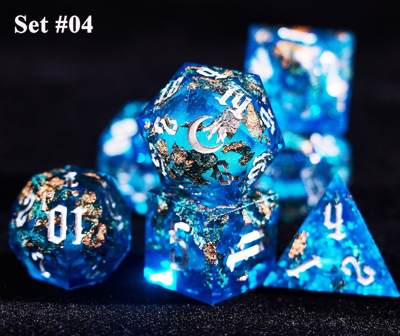 May include: A set of seven blue resin dice with gold flakes and white numbering. The dice feature a celestial design with a crescent moon and stars. The text "Set #04" is in the upper left corner.