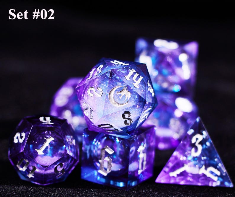 May include: Set #02. A set of seven polyhedral dice with a galaxy design in shades of purple and blue. The dice have white numbering and a silver moon and dragon symbol on the largest die.