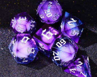 Könnte beinhalten: Ein Satz von sieben polyedrischen Würfeln in Lila- und Blautönen. Die Würfel haben weiße Zahlen und ein galaxieartiges Inneres. Die Würfel sind für Tabletop-Rollenspiele konzipiert.