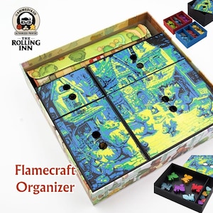 May include: A Flamecraft Organizer box with a colorful dragon-themed design. The box contains multiple compartments and trays for game pieces. The design features dragons, buildings, and a map. The text "Flamecraft Organizer" is visible on the front.